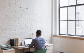 A man sits at his laptop in a home office