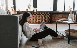 Woman sits in her apartment on her laptop